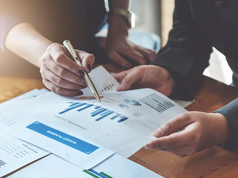 Billede af to personer der sidder og ser på et stykke papir med grafer